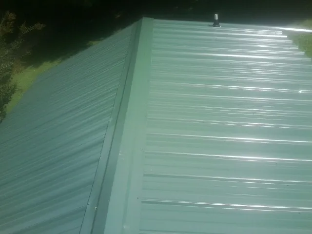 New green metal panels meeting at the ridge of a roof — Flat Roof Repair work by our crew in Pleasantville